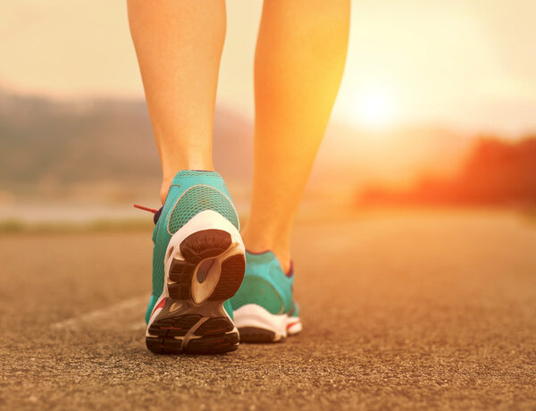 Runner athlete feet running on road