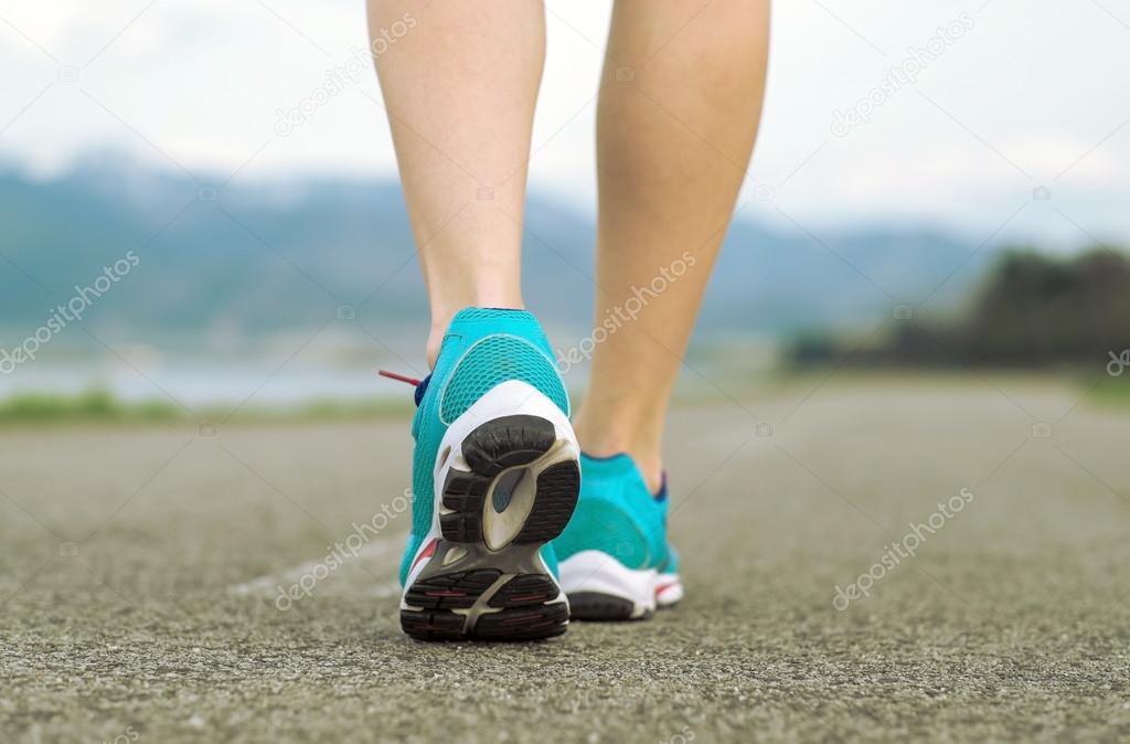 Runner athlete feet running on road