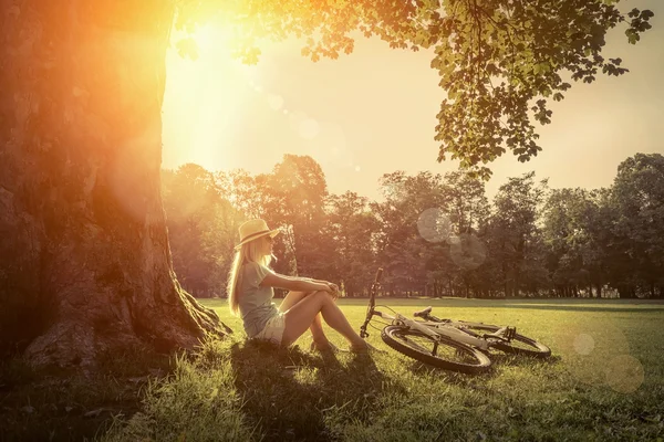 Woman sitting  near her bicycle — Stock Photo, Image