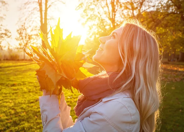 Glückliche Frau mit Blättern im Herbst — Stockfoto