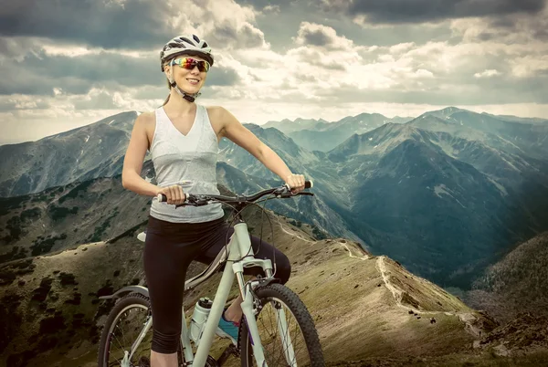 在头盔骑在自行车上的女人 免版税图库图片