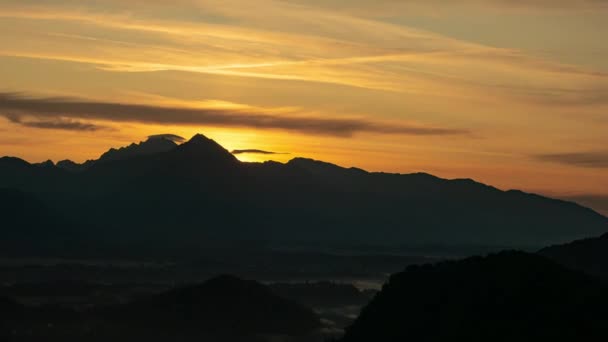 Time-lapse vista sobre o belo nascer do sol sobre as majestosas colinas com o Lago Bled na Eslovénia em uma manhã nebulosa frio. — Vídeo de Stock