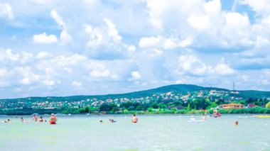 VELENCE, HUNGARY - 06 Ağustos 2019: Güneşli bir yaz gününde Macaristan 'ın Velence gölünde yüzen ve oynayan insanları hızlandırılmış görüş.