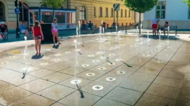 SZEKESFEHERVAR, HUNGARY - 19 Ağustos 2019: Çocuklar ve yetişkinler sıcak bir yaz gününde Macaristan 'ın Szekesfehervar kentindeki çeşmeyle oynuyorlar.