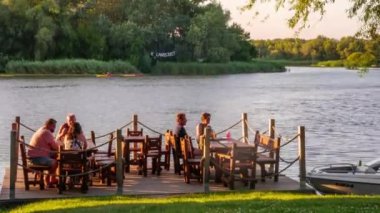 TISZAFURED, HUNGARY - 08 AĞUSTOS 2020: Macaristan 'ın Tiszafure kentindeki Tisza gölünde akşam yemeği yiyen insanların zamansız görüntüsü.