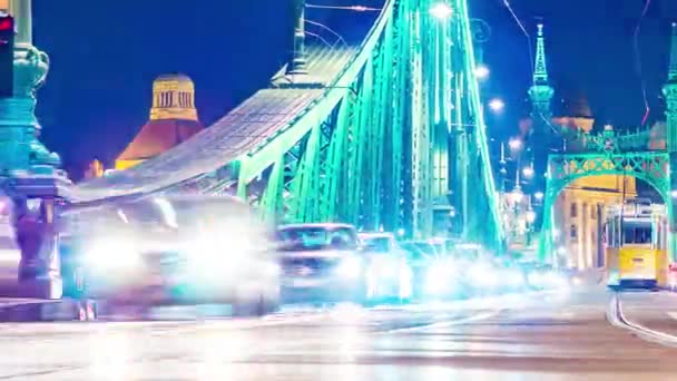 BUDAPEST, HONGARIJE - DECEMBER 14, 2019: Time-lapse zicht op het verkeer op de Fovam plein en de Liberty Bridge 's nachts in Boedapest, Hongarije. — Stockvideo