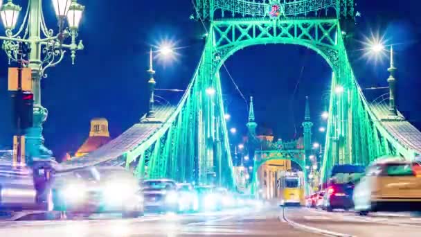 BUDAPEST, HUNGRIA - 14 DE DEZEMBRO DE 2019: Vista temporal sobre o trânsito na praça Fovam e a Ponte da Liberdade à noite em Budapeste, Hungria. — Vídeo de Stock