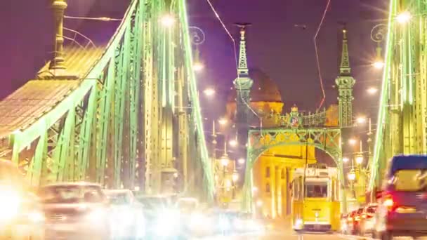 BUDAPEST, HONGARIJE - DECEMBER 14, 2019: Time-lapse zicht op het verkeer op de Fovam plein en de Liberty Bridge 's nachts in Boedapest, Hongarije. — Stockvideo