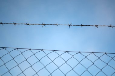 Gökyüzüne karşı dikenli telleri izle.