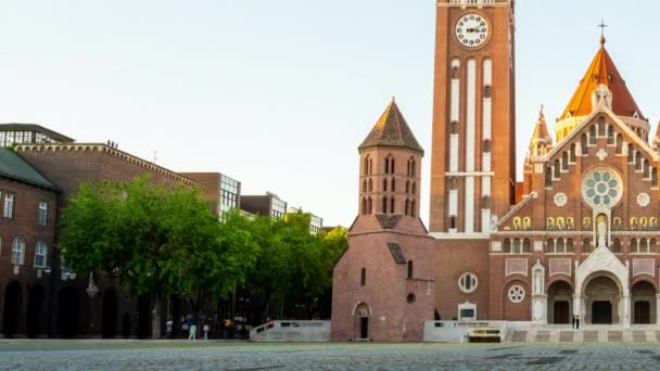 SZEGED, HUNGRIA - 18 de maio de 2021: Vista de lapso de tempo sobre a Igreja Votice e as pessoas na praça em Szeged, Hungria à noite. — Vídeo de Stock