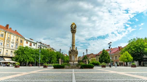 SZOMBATHELY, HONGARIJE - AUGUST 15, 2021: Time-lapse uitzicht op het standbeeld van de Heilige Drie-eenheid of de Szentharomsag szobor op het centrale plein of Fo Square en de mensen op een zonnige, bewolkte dag in Szombathely, Hongarije. — Stockvideo