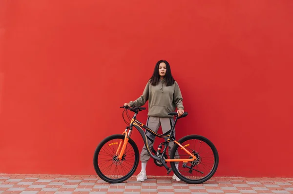 Mulher Elegante Roupas Casuais Fica Com Uma Bicicleta Fundo Parede — Fotografia de Stock