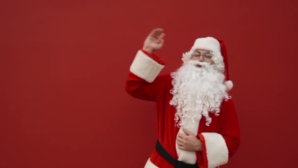 Szczęśliwy Mikołaj Stoi Tle Czerwonej Ściany Jest Witany Uśmiechem Twarzy — Wideo stockowe