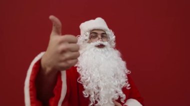 Mutlu noel babalar kamerayı işaret eder ve kırmızı duvarda gülümserler. Noel konsepti. Noel Baba seviyor..