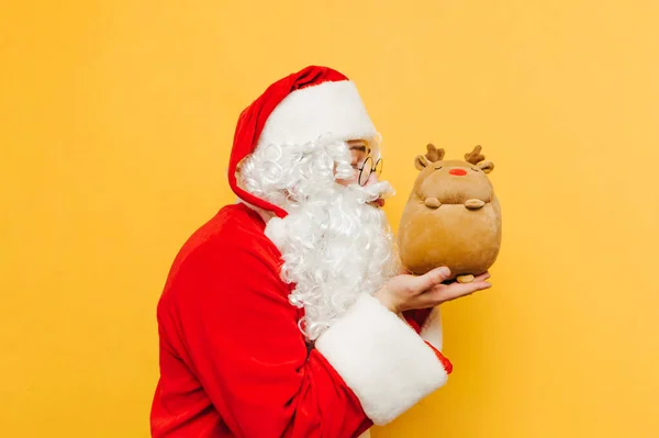 Babbo Natale Divertente Abbraccia Cervo Giocattolo Uno Sfondo Giallo Con — Foto Stock