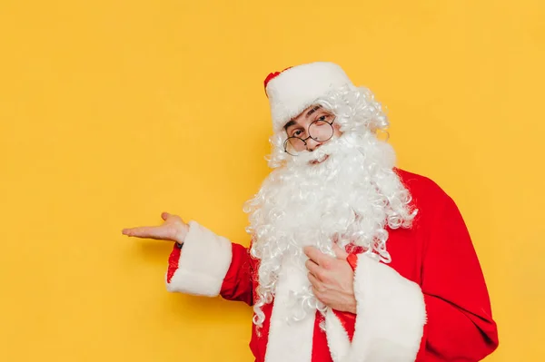 Santa Claus Positivo Está Parado Sobre Fondo Amarillo Sosteniendo Espacio —  Fotos de Stock