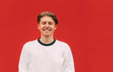 Beyaz kazaklı mutlu genç adam sihirli bir arka plan üzerinde duruyor ve yüzünde bir gülümsemeyle kameraya poz veriyor. İzole edilmiş.