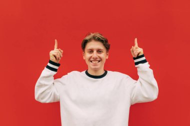 Gündelik giysiler içindeki mutlu genç adam yüzünde bir gülümsemeyle kameraya bakar ve fotokopi çekerken başparmağını kaldırır..