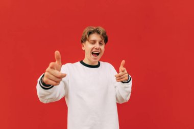 Pozitif adam işaret parmağını kameraya gösteriyor ve yüzünde bir gülümsemeyle bakıyor. Mutlu genç adam seni işaret ediyor ve gülüyor..