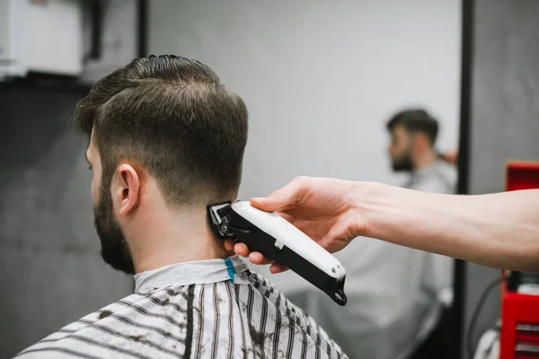 Foto Schließen Friseurhand Mit Haarschneidemaschine Schneidet Haare Eines Bärtigen Erwachsenen — Stockfoto