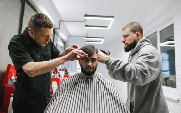 Dos Peluqueros Cortando Pelo Hombre Barbudo Una Elegante Peluquería Ligera —  Fotos de Stock