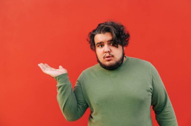 Şişman, sakallı, genç bir adam elinde bir fotokopi çekiyordu. Kameraya ilginç bir ifadeyle bakıyordu..