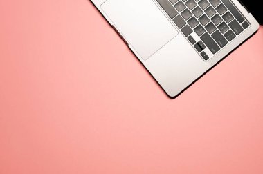 Pembe arka planda, siyah klavyesi ve dokunmatik rampası olan gri, modern bir dizüstü bilgisayarı olan minimalist düz bir fotoğraf..