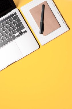 Gri gri modern dizüstü bilgisayarı olan dikey bir düzen, iki basit defter, gri çizgi, ve sarı arka planda bir kopya alanı.