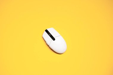 İzole edilmiş sarı arka planda beyaz plastik bir bilgisayar faresinin düz bir fotoğrafı vardı..