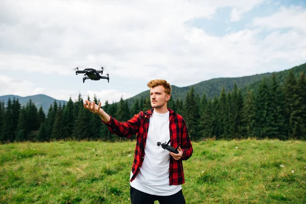 Knappe Jongeman Een Rood Shirt Staat Een Bergweide Een Drone — Stockfoto