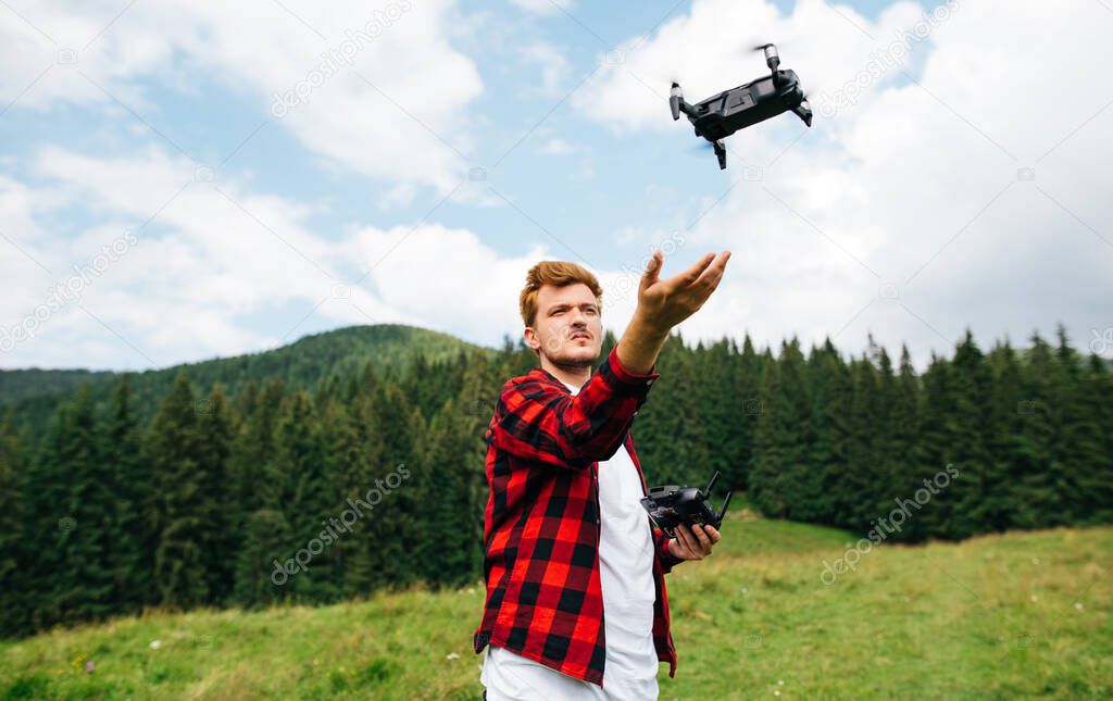 Young man video maker flies a drone in the mountains, launches a drone from his hands. Creating travel content from a drone