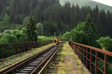 Dağlardaki kale köprüsünde yürüyüş yapan iki güzel turist el ele tutuşuyor. Karpatlar, Ukrayna. Ukrayna 'ya seyahat