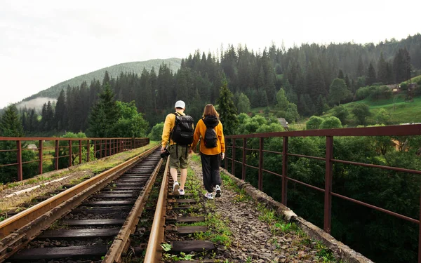 Elegante Casal Hipsters Caminhando Ponte Ferroviária Vorokhta Cárpatos Contra Pano — Fotografia de Stock