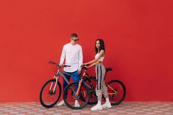 남성과 여성들이 배경에 자전거를 카메라를 포즈를 취한다 사랑하는 사람과 자전거타기 — 스톡 사진