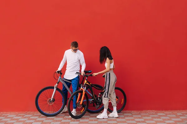 Elegante Jovem Casal Com Bicicletas Ficar Fundo Vermelho Usar Sportswear — Fotografia de Stock