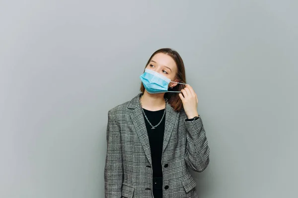 Young Business Woman Stands Gray Background Removes Protective Mask Her — Stock Photo, Image