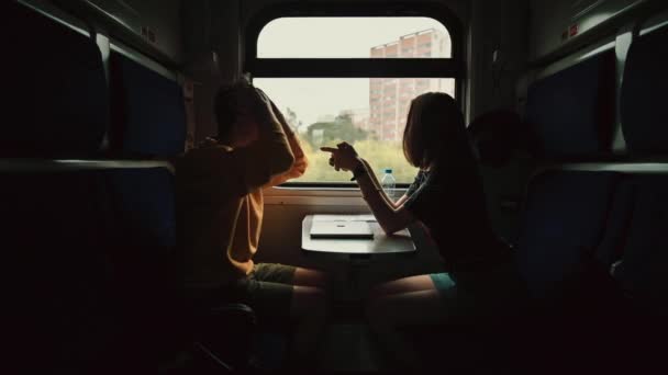 ロマンチックなカップルは夕方に電車のコンパートメントに移動し 彼らの顔に笑顔で通信します 正の男と女が電車に乗って話をする — ストック動画