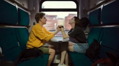 Birbirine aşık pozitif bir çift bir tren kompartımanında oturur ve yüzlerinde bir gülümsemeyle iletişim kurar ve birbirlerinin ellerini tutarlar..