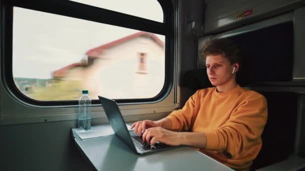 집약적 젊은이가 얼굴에 문제가 헤드폰을 기차대에서 노트북으로 일하고 있었다 프리랜서는기 — 비디오