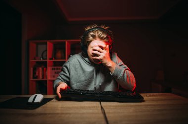 Kulaklık takmış üzgün bir oyuncu kırmızı bir odada bilgisayarın başına oturur ve oyunu kaybettikten sonra ağlar. Genç adam bir video oyunu kaybediyor ve yüzünü utançla örtüyor..