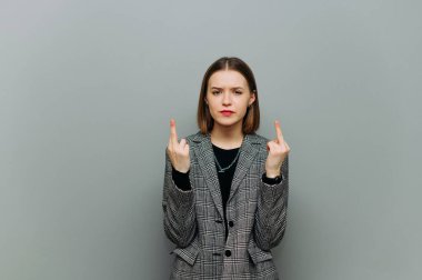 Serious woman in smart casual clothes shows fingers gesture 