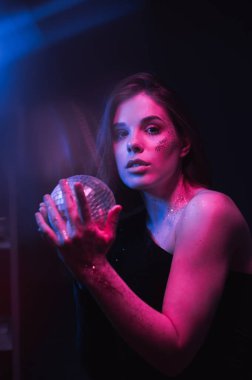 Elinde mor ve mavi bir ışıkla kameraya poz veren parlak makyajlı bir kadının ters dalga portresi..