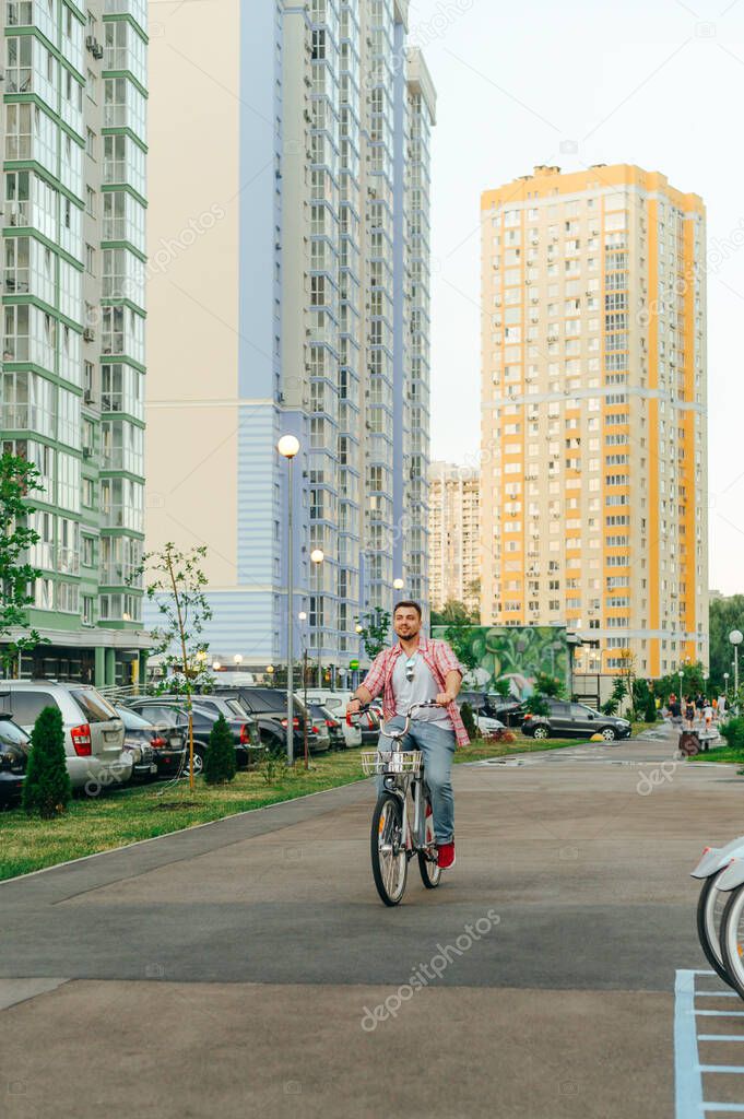 Adult man in bright casual clothes is riding a bicycle on the street and smiling. Happy man rides a bicycle on a shering bicycle and rejoices