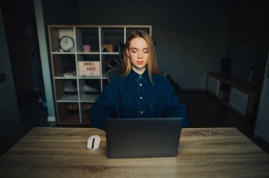 Evde dizüstü bilgisayarla çalışan çekici serbest çalışan bir kadın. Dikkatlice ekrana bakıyor. İnternette çalış.