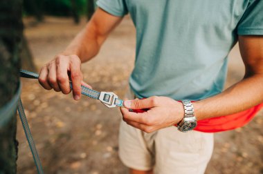 Hamakta el örgüsü ören erkeklerin yakın bir fotoğrafı. Erkeklerin elleri askıları birbirine bağlar.