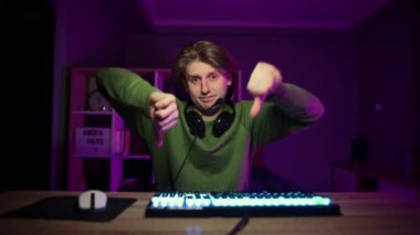 Canı sıkkın oyuncu parmağını aşağı uzatıyor ve evde bilgisayar oyunları oynamaya devam ediyor. Flaman oyun sırasında hoşnutsuz bir jest gösterir.