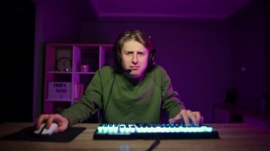 Evde mor bir gece geçiren bir odada bir sandalyede oturan, kaybettiği için bilgisayarda oynarken ağlayan kulaklıklı bir oyuncu. Adam çevrimiçi bilgisayar oyunlarından umudunu kesmiş..