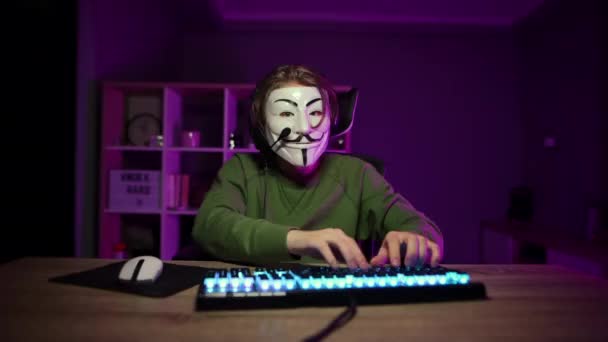 Yüzünde Isimsiz Bir Maske Kafasında Kulaklık Olan Bir Adam Bilgisayar — Stok video