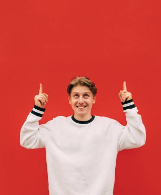 Kırmızı arka planda izole edilmiş beyaz giysili mutlu adam fotokopi odasına bakıyor ve gülümsüyor..