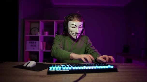 匿名のマスクの男は コンピュータとストリーム上の自宅で夜にビデオゲームをプレイします フォークスの装いでゲーマーストリームオンラインゲーム — ストック動画